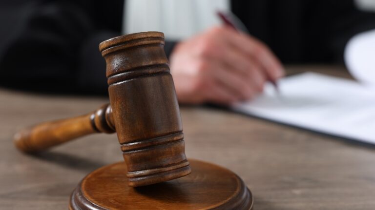 Judge with gavel writing in papers at wooden table