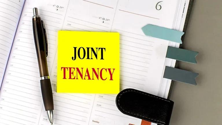 Open planner with blue page markers, black pen, and yellow sticky note reading "JOINT TENANCY